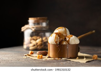 Ice cream balls in a cooper saucepan with caramel on brown background.Close up of sweet desert in freeze motion.