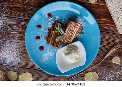 Ice cream and cake on a blue plate on a brown wooden background