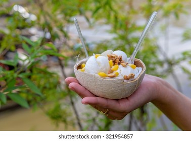 Ice cream in a coconut shell with hand hold.