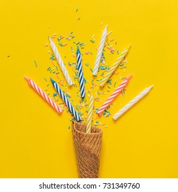 An Ice Cream Cone, Birthday Candles And Confetti On Yellow Background