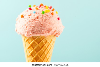 Ice cream cone close-up. Pink Icecream scoop in waffle cone over blue background. Strawberry or raspberry flavor Sweet dessert decorated with colorful sprinkles, closeup - Shutterstock ID 1099567166