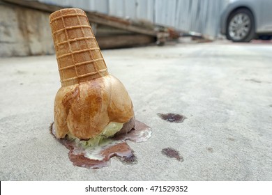 ice cream cone dropped on the concrete floor and melting.