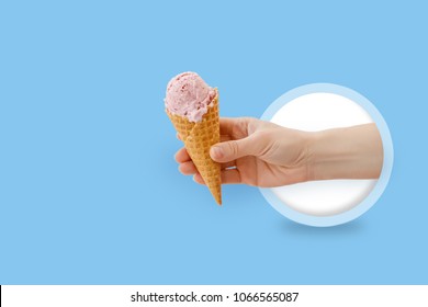Ice cream cone in hand on blue background.