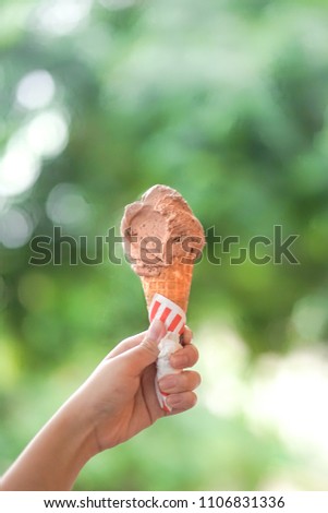 Ice cream cone. A lady's hand holding a chocolate ice cream cone in the summer day.