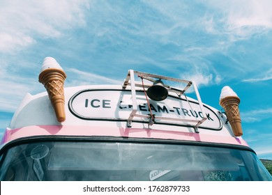 Ice cream cone with a pink ice cream truck or van in the background.