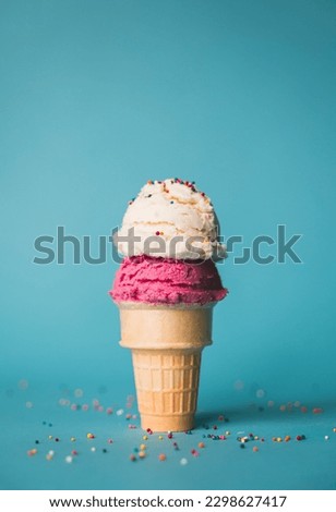 Ice cream cone with two scoops and sprinkles on blue background.
