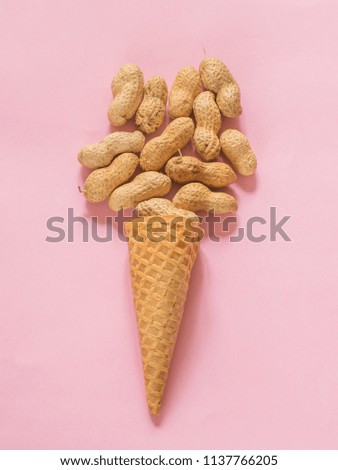 Ice cream cone with unpeeled peanuts on pink background