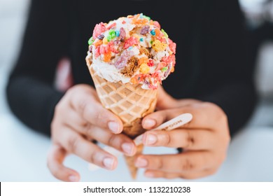 Ice cream cone with vanilla, cookie and cream, or chocolate ice cream. waffle cone being held by a girl. colorful cereal toppings for vibrance. perfect for hot summer days or winter  - Powered by Shutterstock