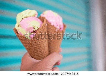 Ice cream cone. The woman holding the ice cream by hand.