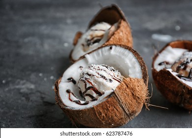 Ice cream with desiccated coconut and chocolate syrup in halves of nut on grunge background