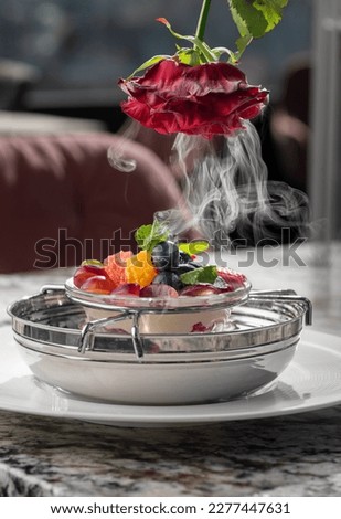 Ice cream dessert with berries and rose petals frozen in nitrogen. Dessert recipe concept, serving in the restaurant hall.