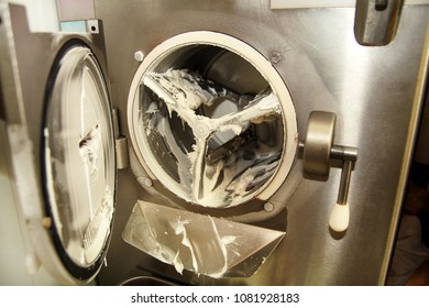 At ice cream factory is cleaning ice cream maker machine from the ice cream leavings. Preparation of ice cream.