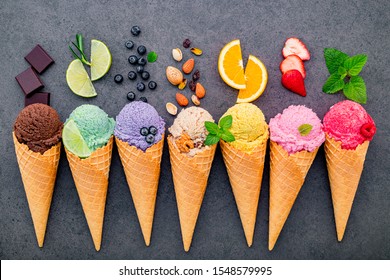 ice cream flavor in cones blueberry ,lime ,pistachio ,almond ,orange ,chocolate ,vanilla and coffee set up on dark stone background . Summer and Sweet menu concept.