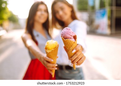 Ice cream in the hands of beautiful young girls. Two female friends eat ice cream while walking in the park. Summer and vacation concept. - Powered by Shutterstock