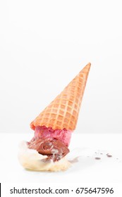 Ice cream on the ground. Chocolate, vanilla and strawberry ice cream cone dropped on floor