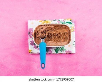 Ice Cream Scoop In Chocolate Ice Cream Tub On Napkin On Pink Background