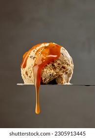 ice cream scoop with flowing melted caramel sauce drop on dark grey wall background