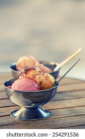 Ice cream in two retro metal bowls on a wooden table. 