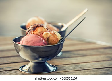 Ice cream in two retro metal bowls on a wooden table. 