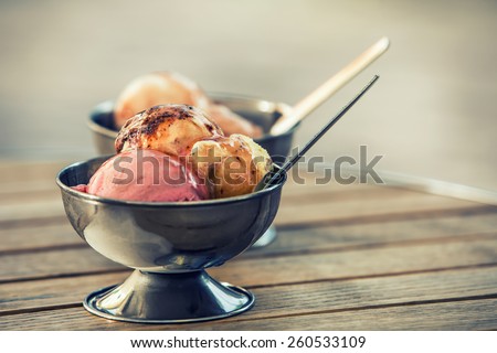 Ice cream in two retro metal bowls on a wooden table. 