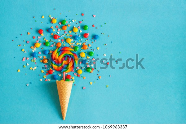 アイスクリームのワッフルコーンとカラフルなロリポップ 多彩色のお菓子の散り散り お菓子のトッピング 青の背景 の写真素材 今すぐ編集