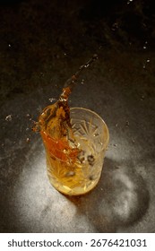 Ice cube fall into a crystal glass with whiskey. Copy space.