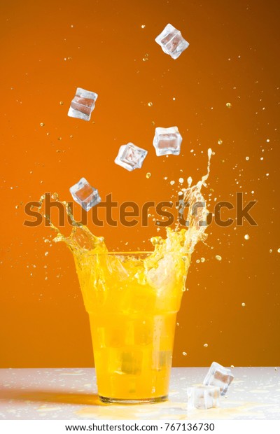 ice cube splash\
in a glass with orange soda