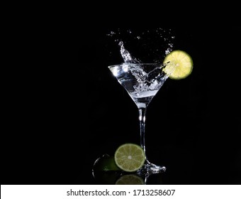 ice cube splash in martini glass with lime on black background
