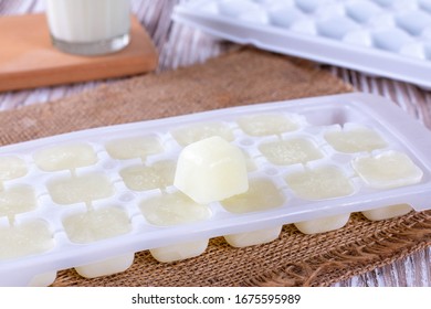 Ice Cube Tray With Frozen Milk On A White Wooden Table, Closeup