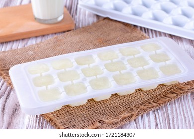 Ice Cube Tray With Frozen Milk On A White Wooden Table, Closeup