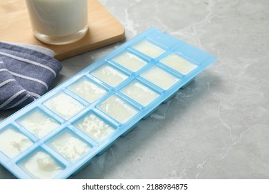 Ice Cube Tray With Frozen Milk On Grey Table