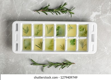 Ice cube tray with herbs frozen in oil and fresh rosemary on grey background, flat lay - Powered by Shutterstock