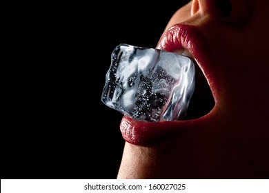 Ice cube in a woman's mouth against black background.