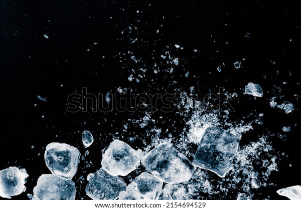 Ice\
cubes crush on black background. Chill\
backdrop.