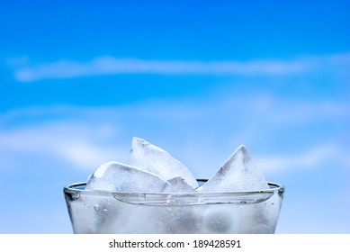 Ice Cubes In A Glass Of Fresh Water, With A Cloudy Summer Sky