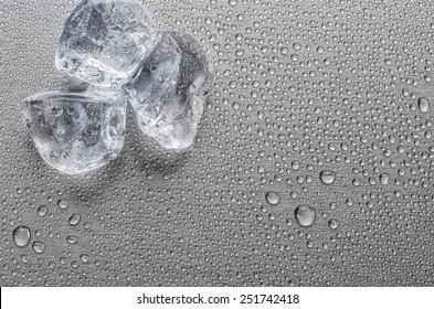Ice cubes on a metallic surface with droplets