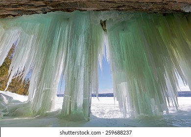 Ice Curtains Drape From A Cavern Entrance On Lake Superior's Grand Island In Munising Michigan. Pictured Rocks National Lakeshore Can Be Seen In The Background Of This Winter Scene.