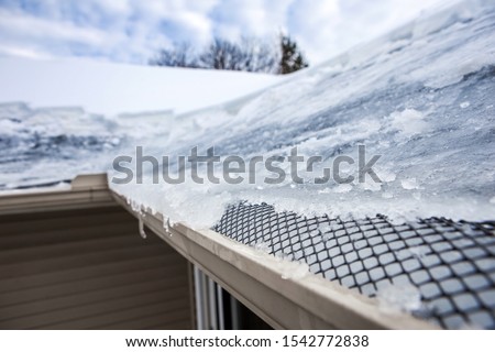 Ice dam in gutter and ice frozen on roof in winter