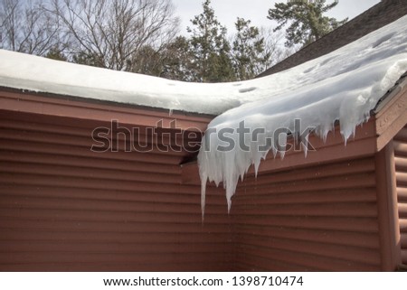 Ice Dam On Roof. Shingle roof on home with icicles and ice dam starts a leak on the roof. 