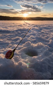 Ice Fishing On A Lake In Norway At Sunset.