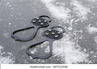 Ice Grippers Cleats For Shoes And Boots On Slippery Road With Frozen Puddle Covered With Ice. Anti Slip Shoe Grip Crampons Spikes For Snow And Ice Make Winter Walking Safer And Provide Stability 