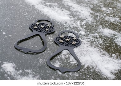 Ice Grippers Cleats For Shoes And Boots On Slippery Road With Frozen Puddle Covered With Ice. Anti Slip Shoe Grip Crampons Spikes For Snow And Ice Make Winter Walking Safer And Provide Stability 