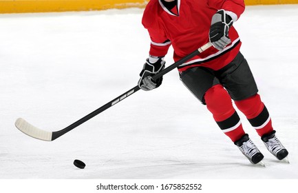 Ice hockey player dribbling puck on rink