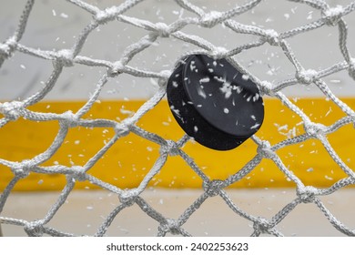 An ice hockey puck hitting the back of the net as it scores a goal