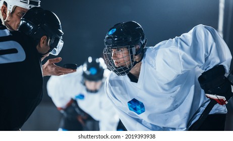Ice Hockey Rink Arena Game Start: Two Professional Players Aggressive Face off, Sticks Ready. Referee Holds the Puck. Intense Competitive Game Wide of Brutal Energy. Close-up Portrait Shot.