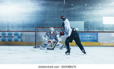 Ice Hockey Rink Arena: Goalie Is Ready To Defend Score Against Forward Player Who Shoots Puck With Stick. Forwarder Against Goaltender One On One. Tension Moment In Sport Full Of Emotions.