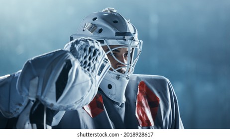 Ice Hockey Rink Arena: Portrait Of Brutal Professional Goalkeeper, Seriously Looking. Focused Goalie, Determined To Win. Confident Champion Athlete. Close-up Portrait Shot