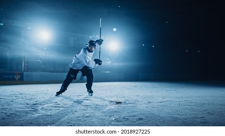 Ice Hockey Rink Arena: Professional Player Shooting, Hitting, Stricking The Puck With Hockey Sticks. Athlete Scoring A Goal. Dramatic Wide Shot, Cinematic Lighting.