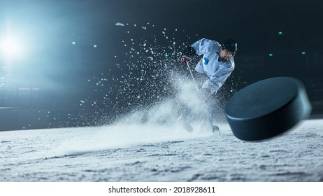 Ice Hockey Rink Arena: Professional Player Shooting the Puck with Hockey Stick. Focus on 3D Flying Puck with Blur Motion Effect. Dramatic Wide Shot, Cinematic Lighting.