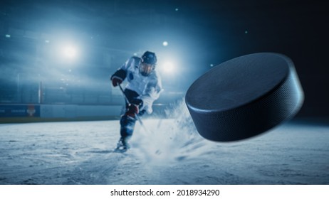 Arena de pista de hockey sobre hielo: Jugador profesional disparando el Puck con palo de hockey. Enfoque en el puente volador 3D con efecto de movimiento de desenfoque. Dramática, Amplio Disparo, Iluminación Cinemática.